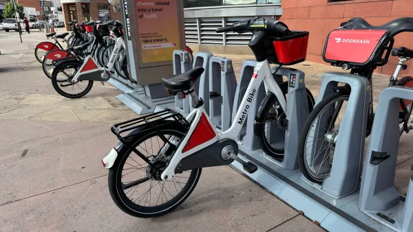 Several bicycles at a docking station on a street.