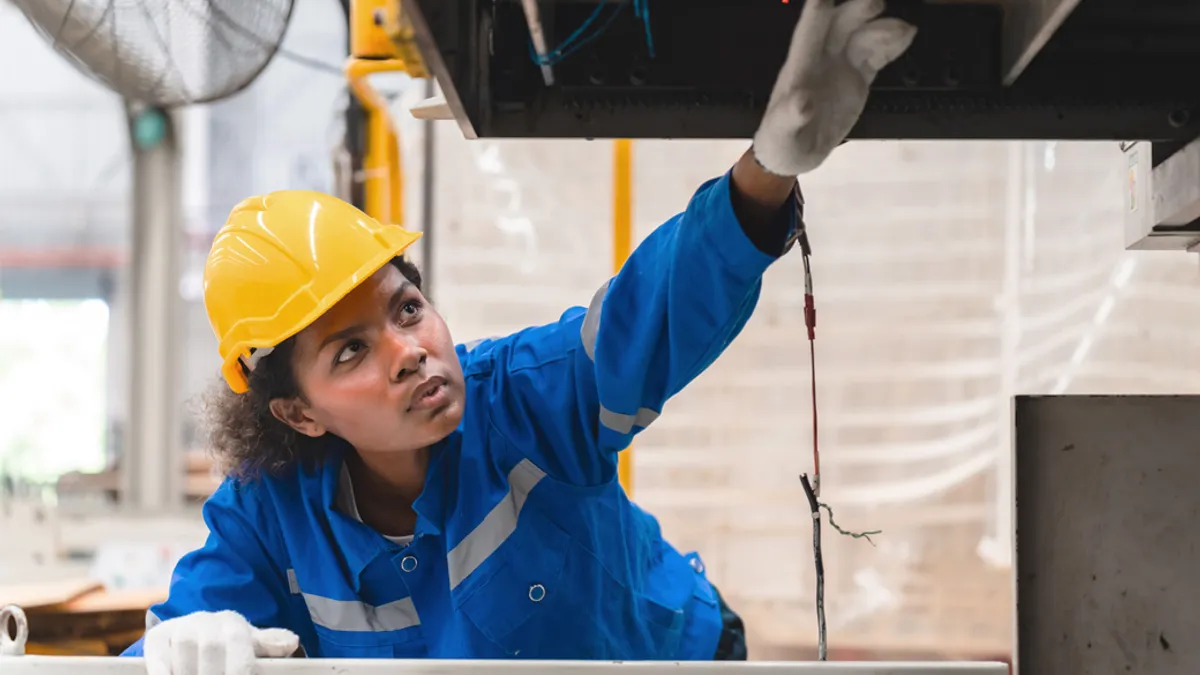 Woman in yellow hard hat and blue uniform.