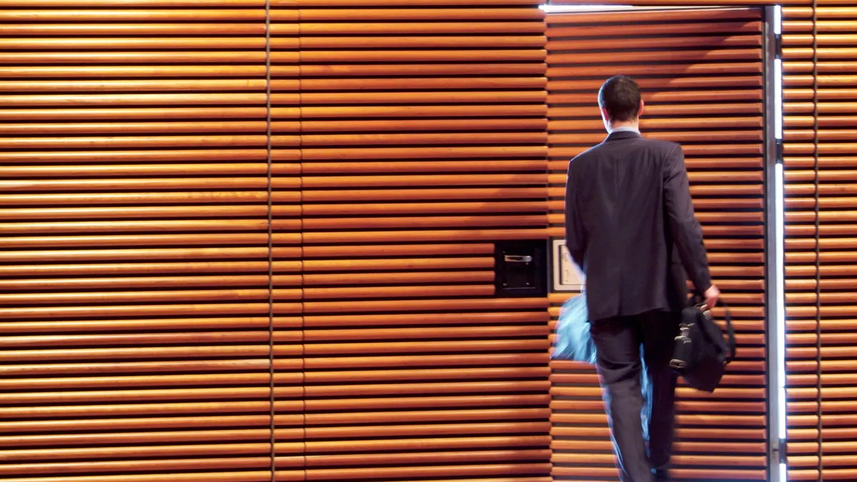 A businessman is exiting through a door in an office with a modern design.