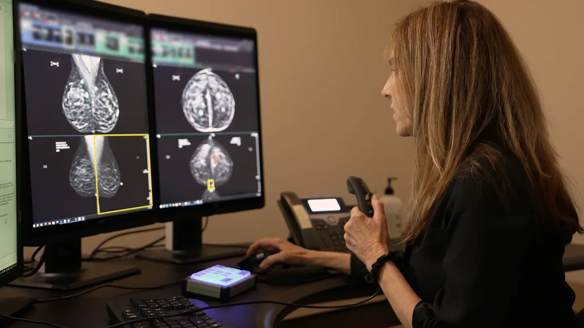 A picture of a women looking at mammography images on a computer in an office setting.