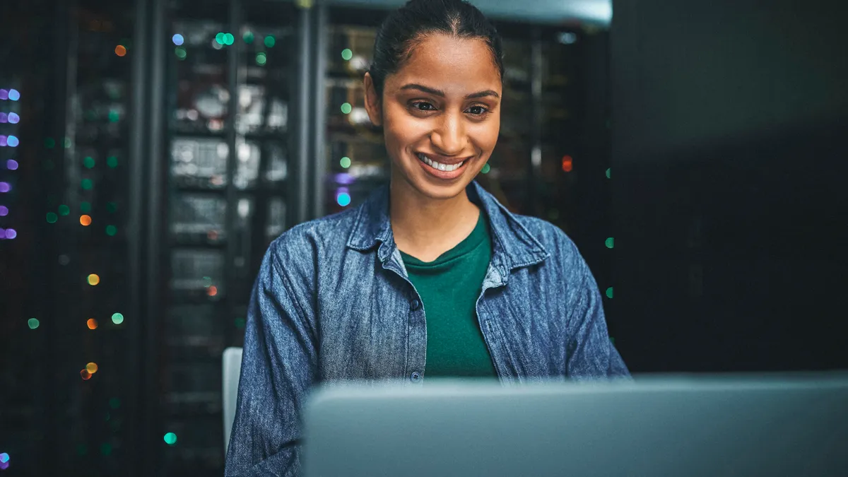 Shot of an IT technician in a server room and using a laptop