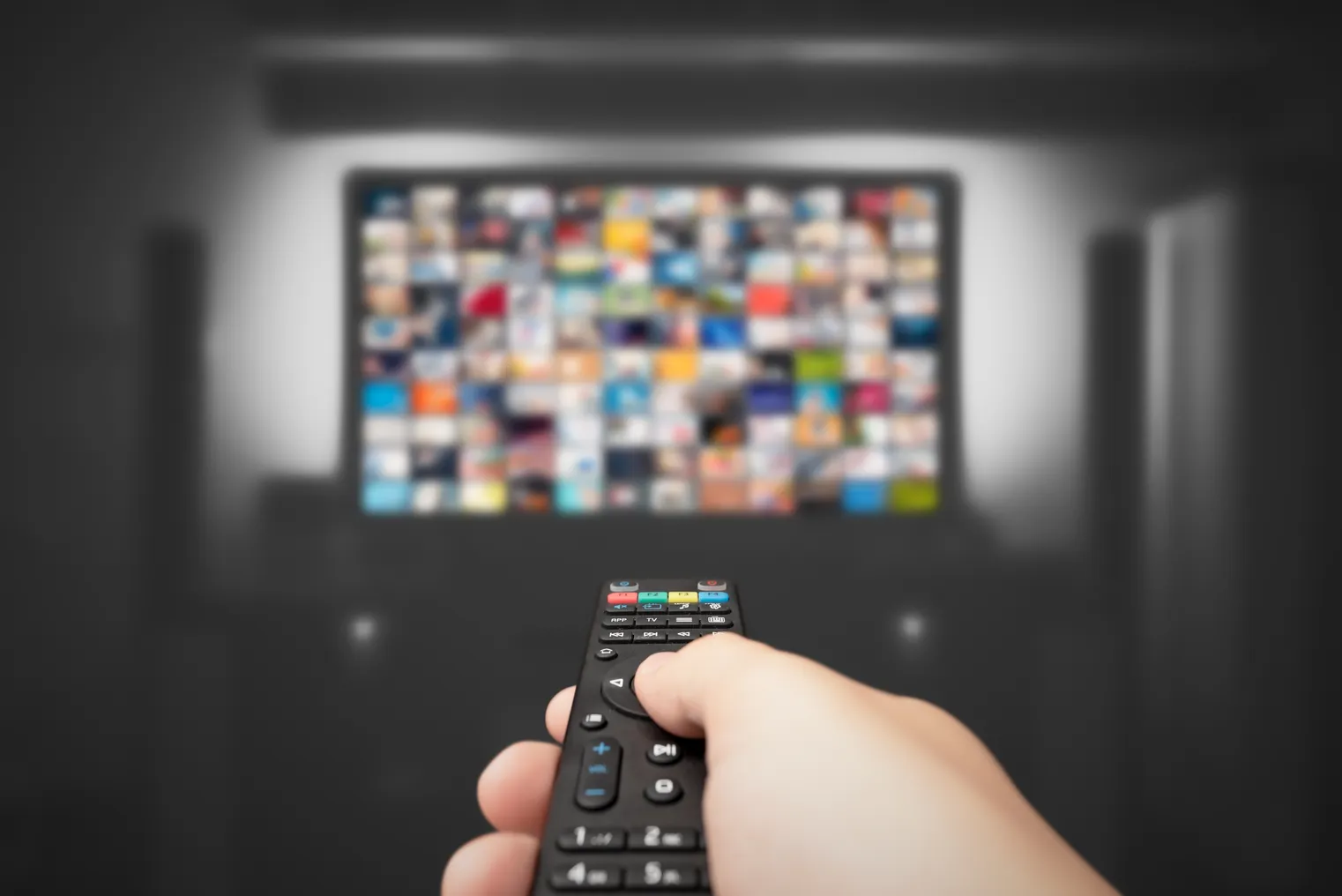 A TV remote points up at a blurred-out screen.