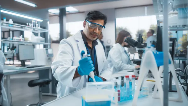 Research scientist using a micropipette to mix liquid in a test tube in a laboratory.