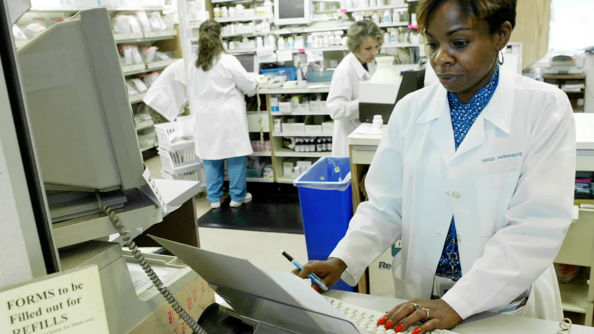 A pharmacist looks at prescription orders on a screen