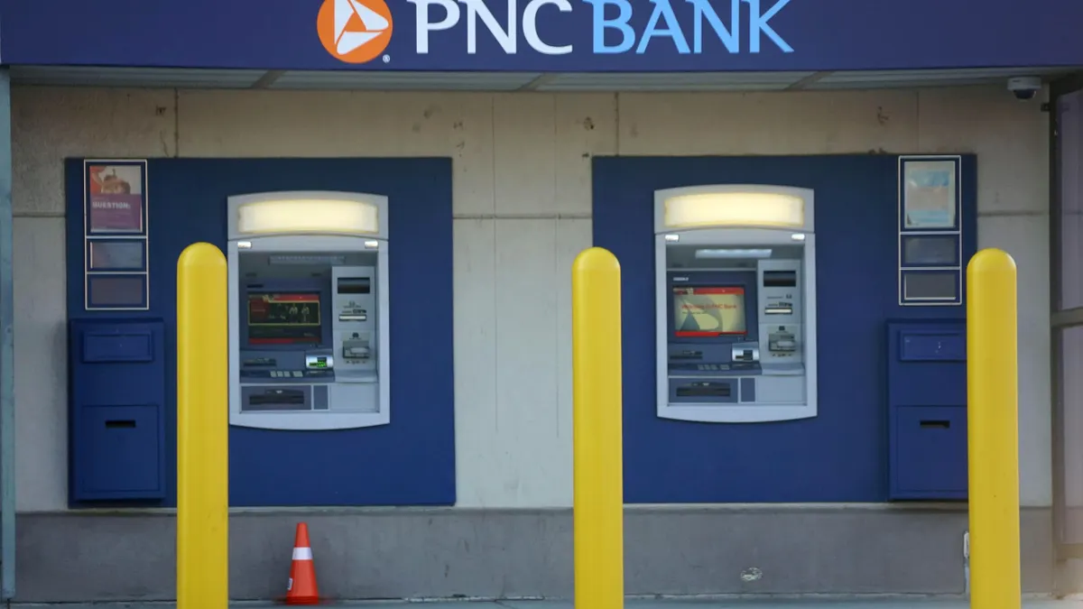 Two blue ATMs are housed within a modern facade featuring the PNC logo above and are accessible from the sidewalk. 
