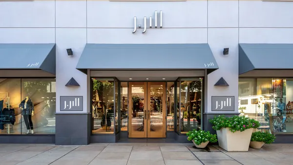 A retail store with J.Jill branding depicted from the sidewalk, featuring large planters.