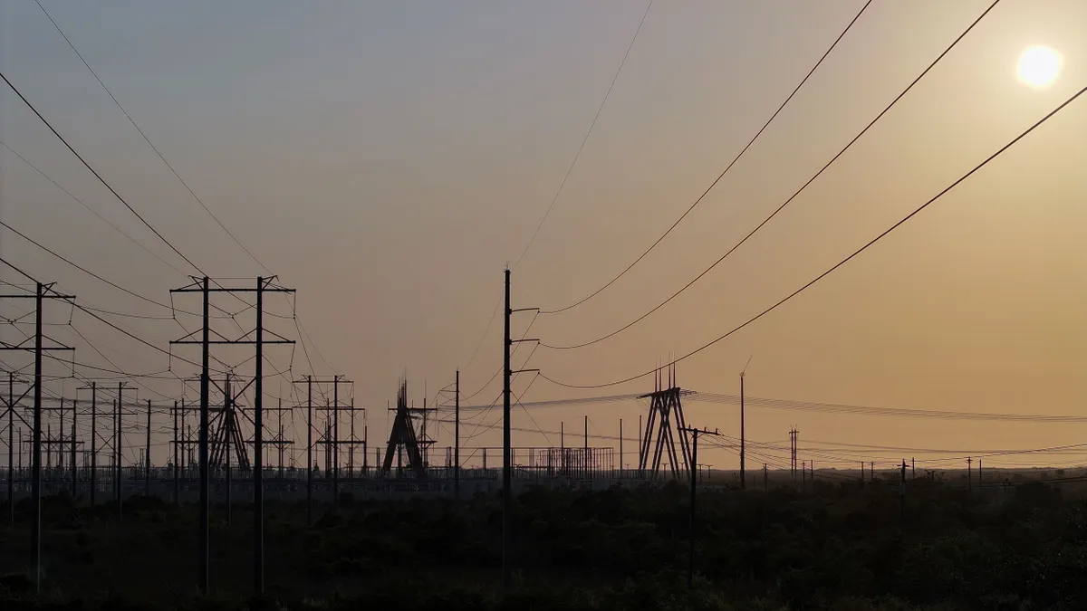 High voltage power lines seen in silhouette at sunset