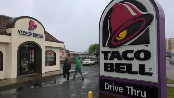 Two people walk towards a Taco Bell restaurant
