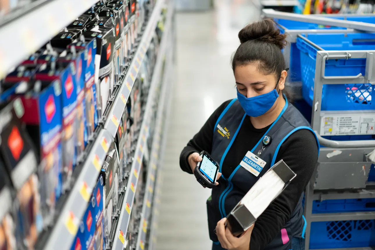 A worker in a retail store using a phone while working.