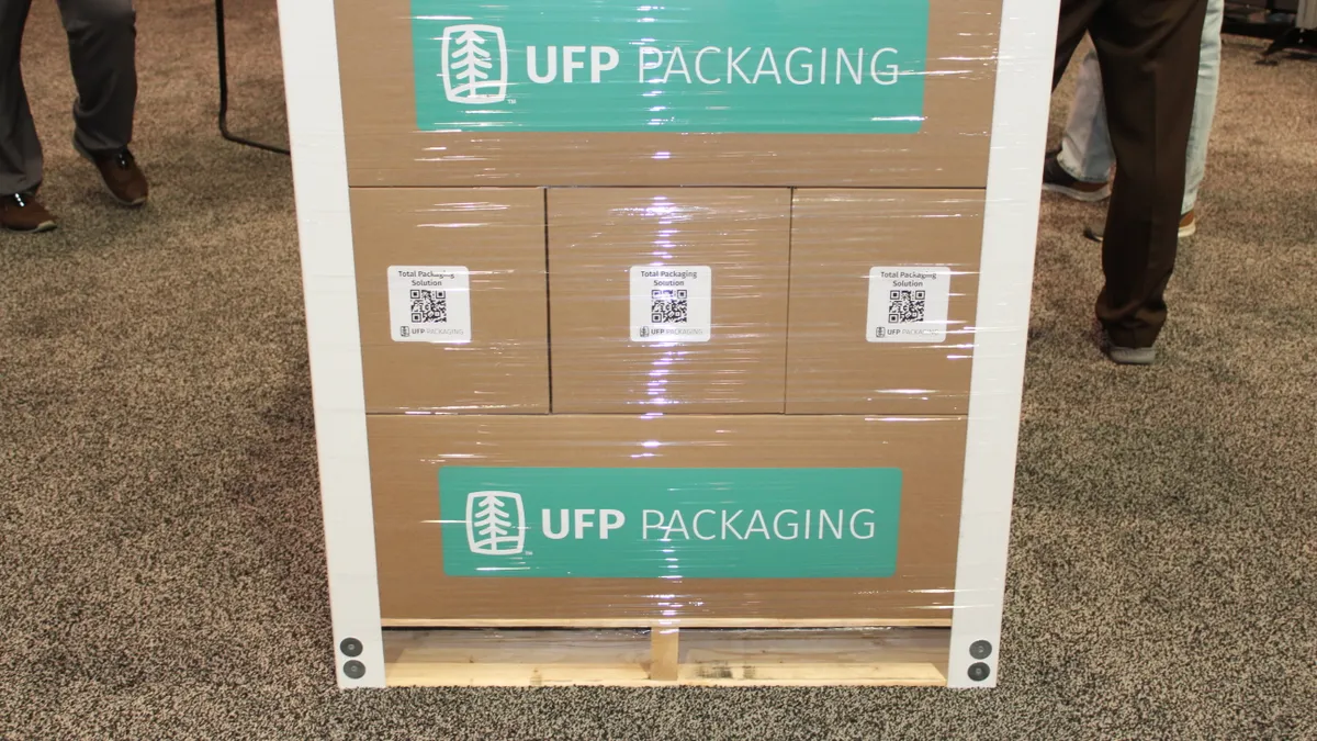 Cardboard boxes displaying UFP Packaging's logo are bundled together on a pallet and covered with plastic wrap.