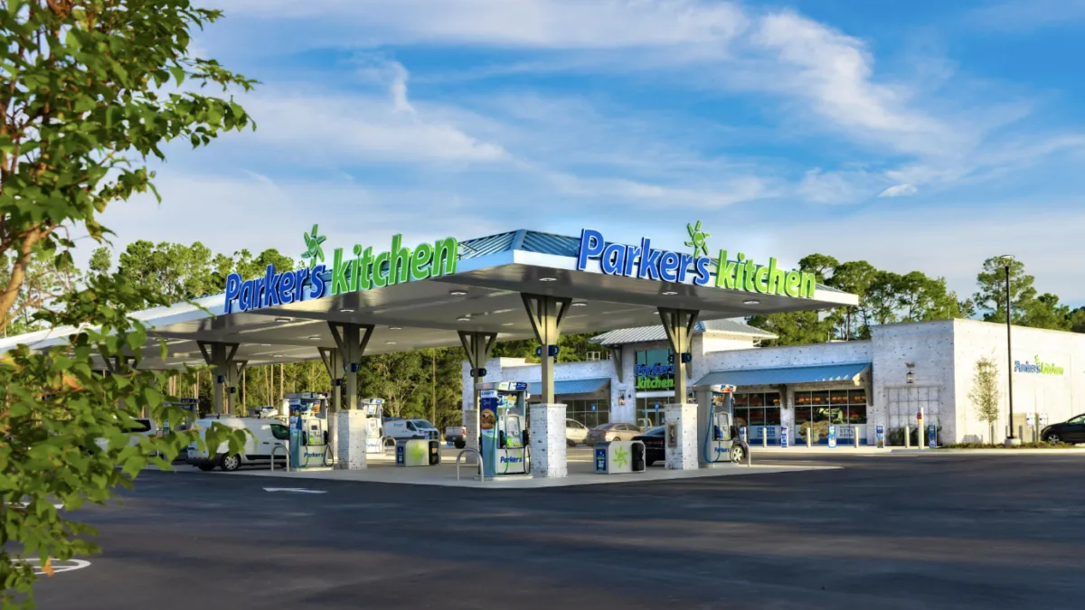 A photo of the exterior of a gas station and convenience store. Signs on the fuel canopy and store say Parker's Kitchen.