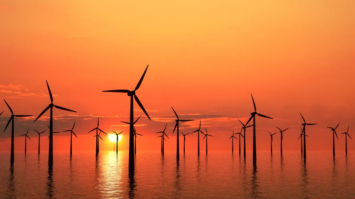 Wind turbines in the ocean at sunset.