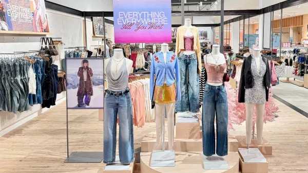 The interior of a clothing store, with headless mannequins in the front.