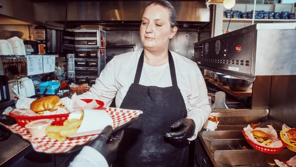 A restaurant worker serving a couple of plates in the restaurant kitchen.