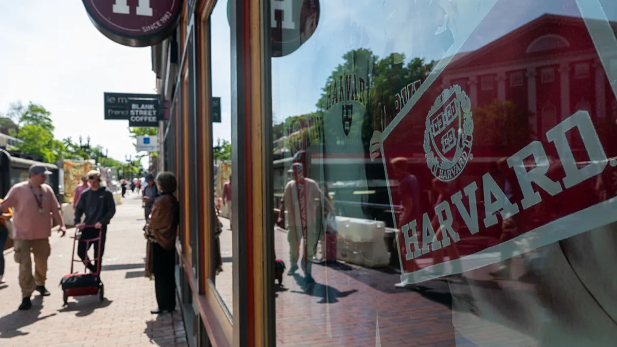 People walk past a shop with Harvard University merchandise.