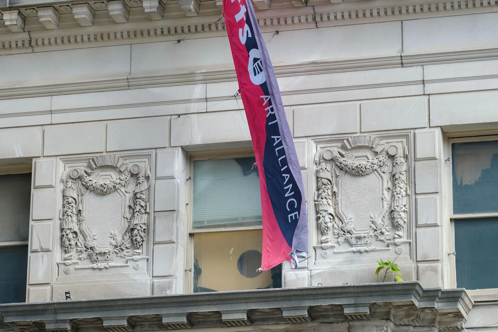 Photo of a red and blue flag in front of a stone building.