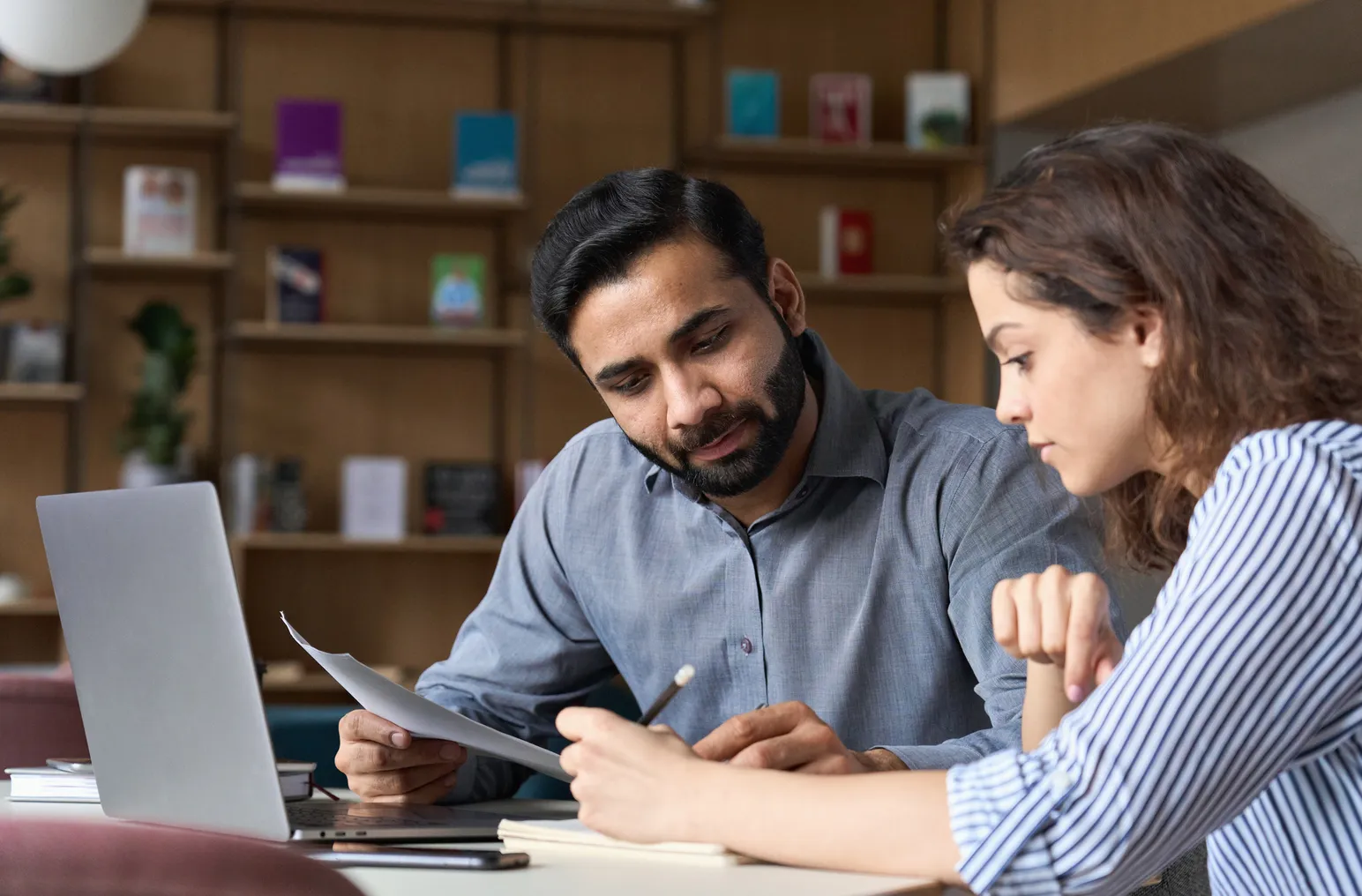 Two people work together in an office looking at papers.