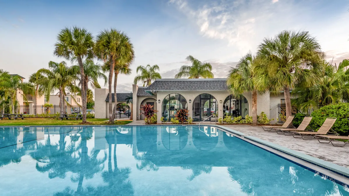 A pool surrounded by chairs at an apartment community.