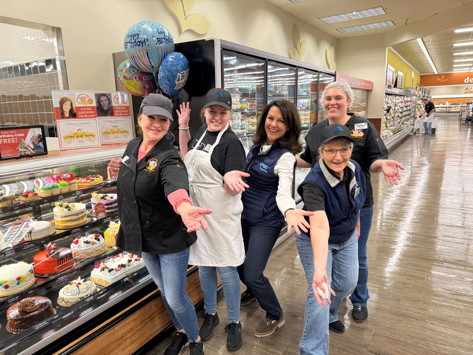 A group of people standing next to a bakery counter in a grocery store.