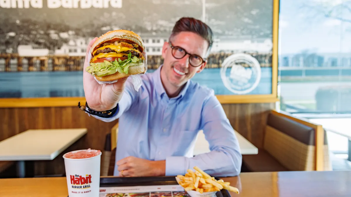 A photo of Jack Hinchliffe, global CMO for Habit Burger, holding a burger made by that brand.