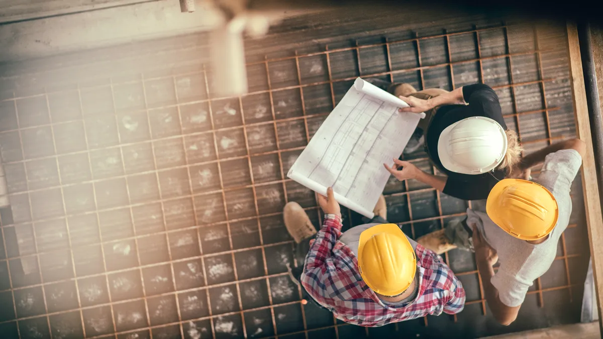 High angle view of three people with helmets working on a construction site,