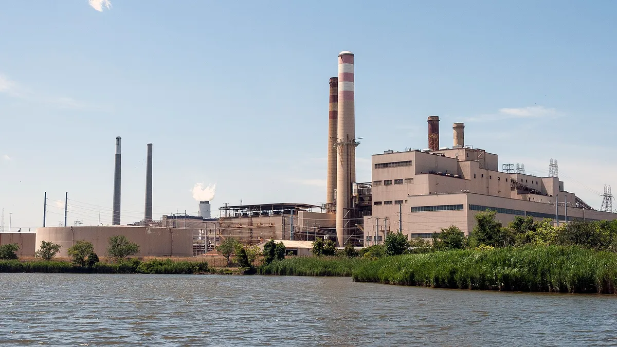 A power plant with smoke stacks at the edge of a river.