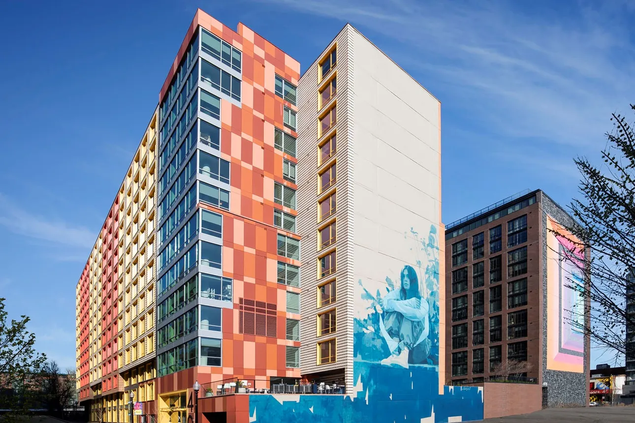 An apartment building with a mural of a woman on the side.