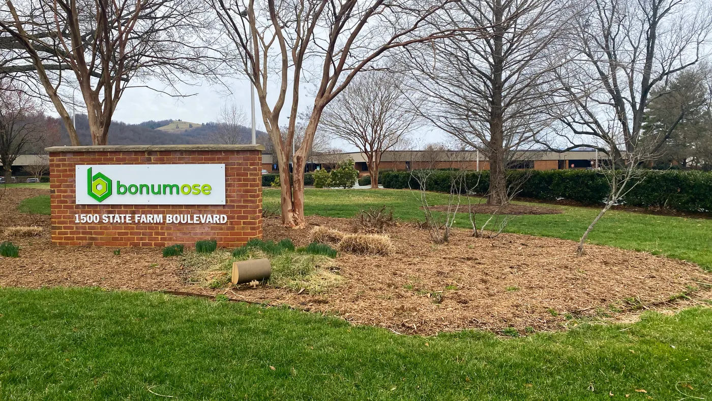A Bonumose sign sits in front of a large brick headquarters building.