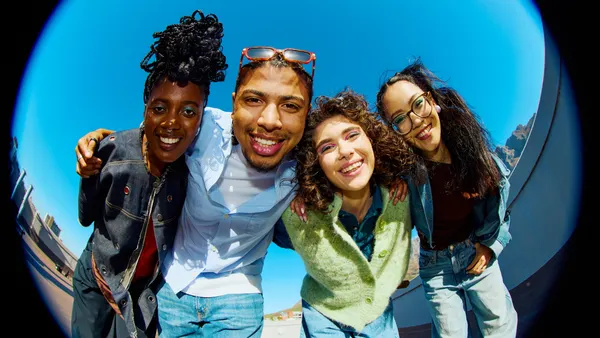 Group of diverse young adult friends smiling with arms around each other on a rooftop