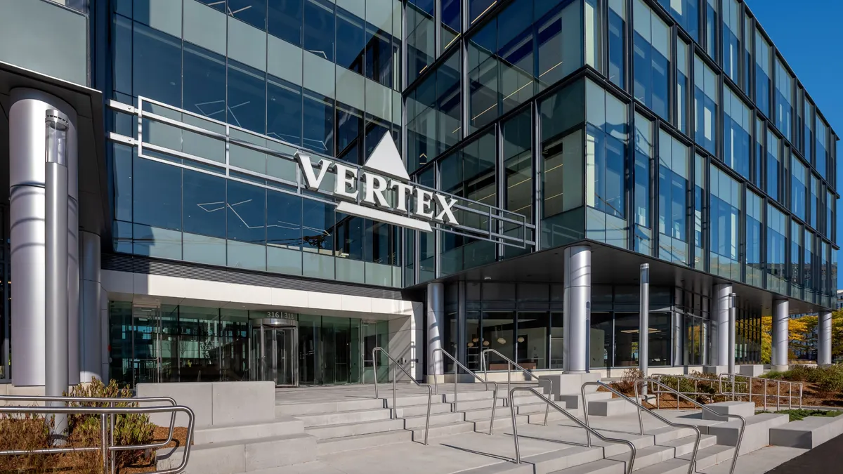 A sign spelling Vertex hangs over an office building entrance.