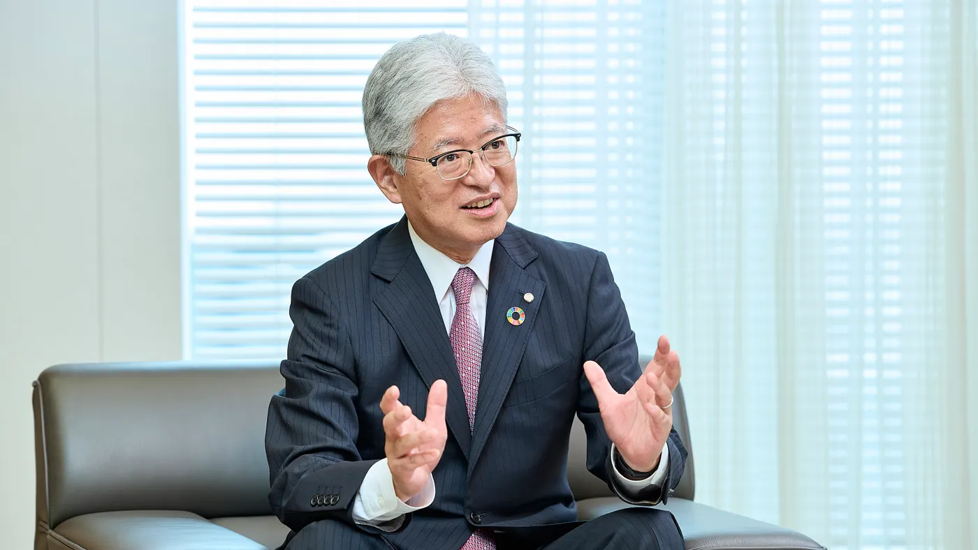 A person in a business suit gestures while speaking.