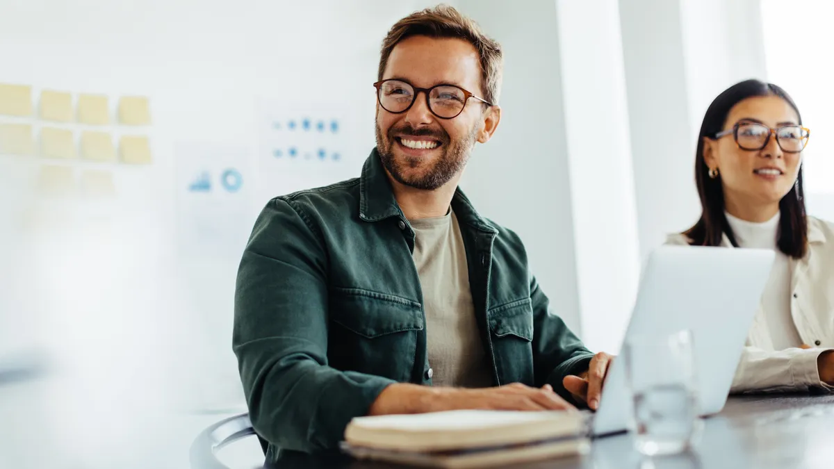 Happy business man listening to a discussion in an office boardroom.