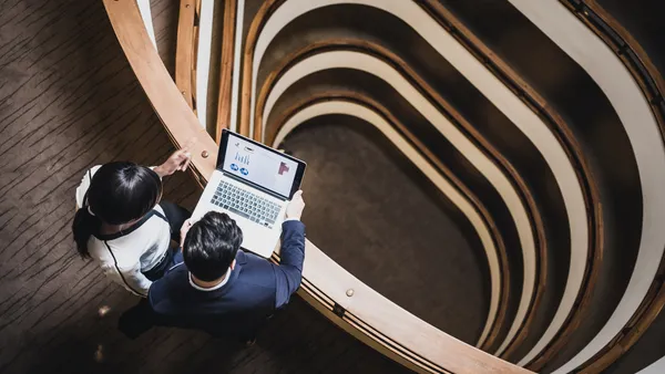 Two people look at a laptop, as seen from overhead.