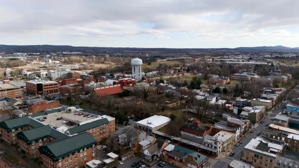 An aerial view of town and residential buildings and trees with a water tower in the distance.