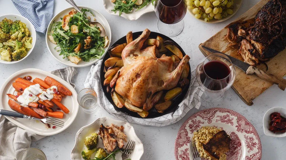 Overhead view of a big, festive dinner with a roasted chicken and various side dishes.