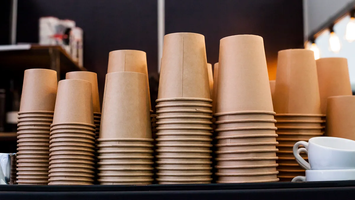 stacks of brown paper cups in a row in a coffeeshop setting