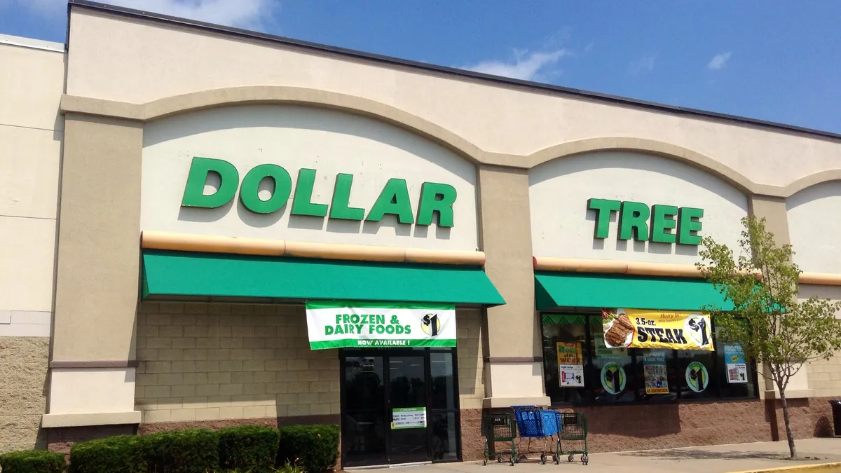 Shopping carts and a small tree outside of a dollar store with green awnings.