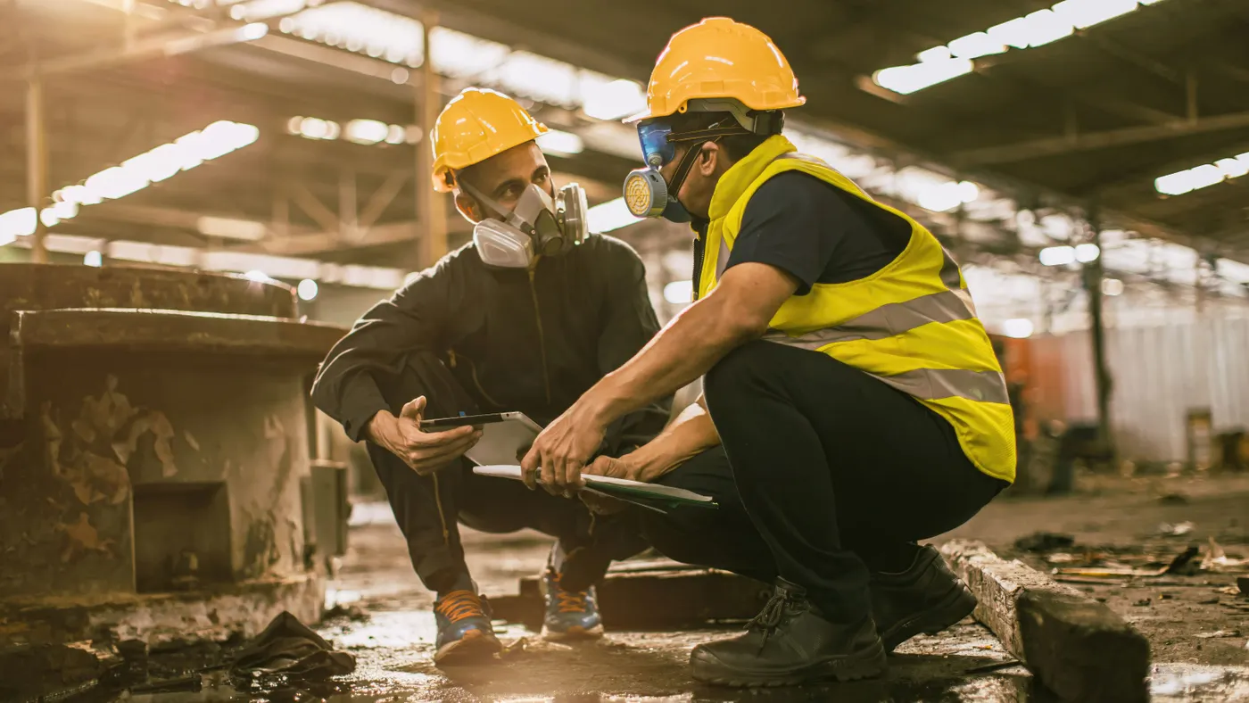 Two construction workers wear respirators on a jobsite.