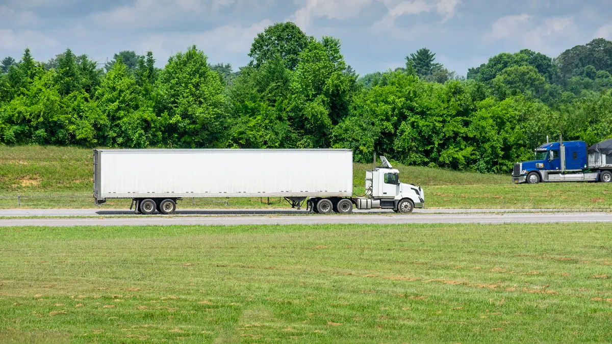 Two heavy trucks meet on an interstate during a summer morning.