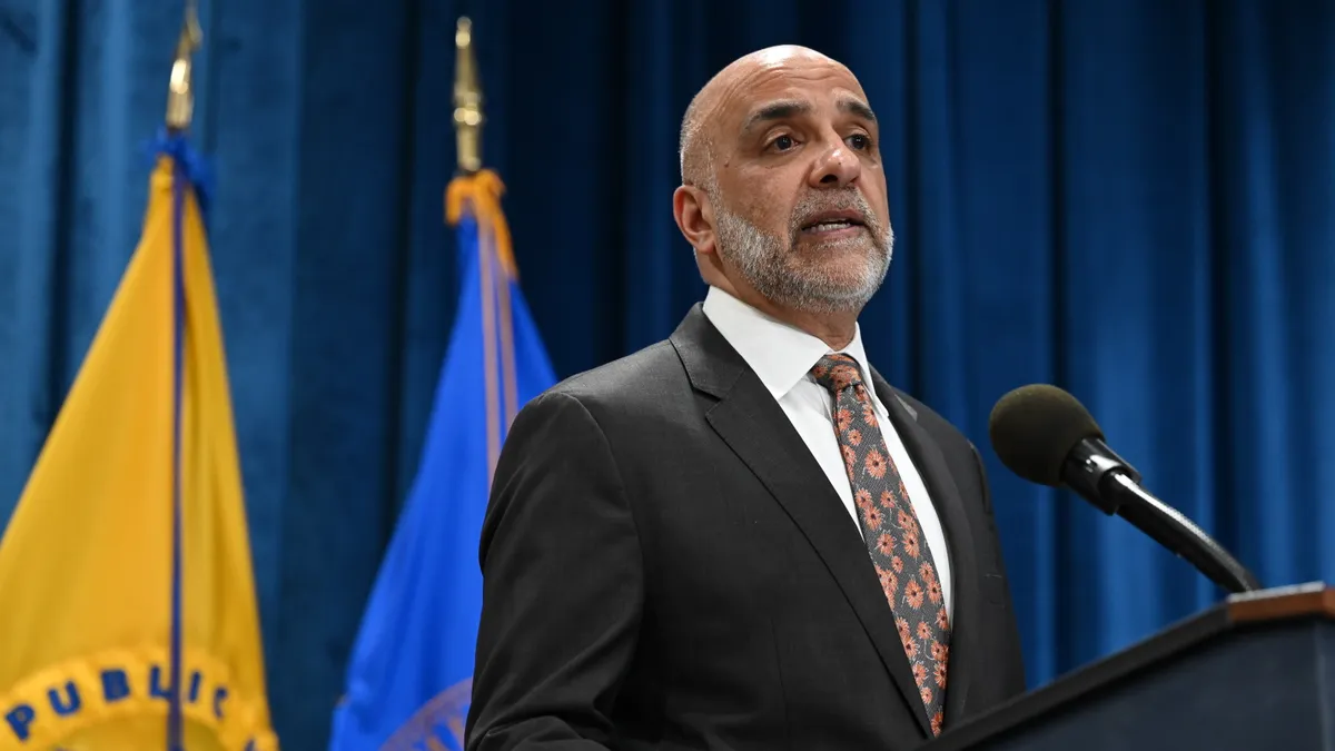 ONC head Micky Tripathi stands behind a podium.