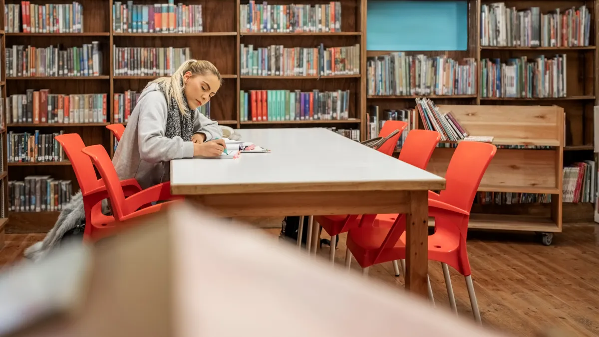 A college student reads a book in the library.