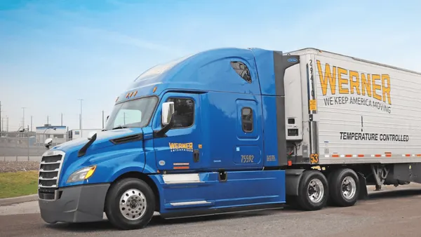 A blue freight truck parked on a road.