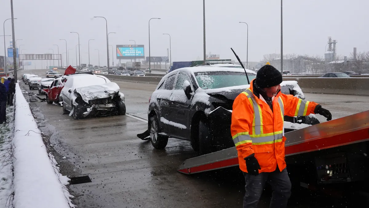 A car with front-end damage is being loaded onto a flatbed truck while several more crashed vehicles are seen behind it on an expresway near downtown Chicago.