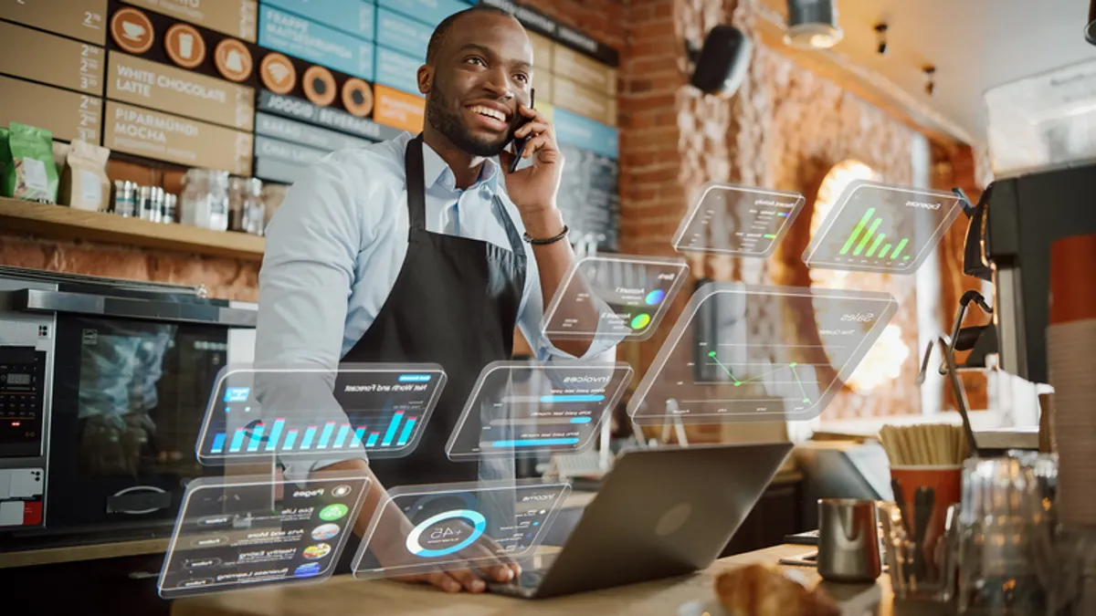 Coffee shop owner using computer and talking on phone