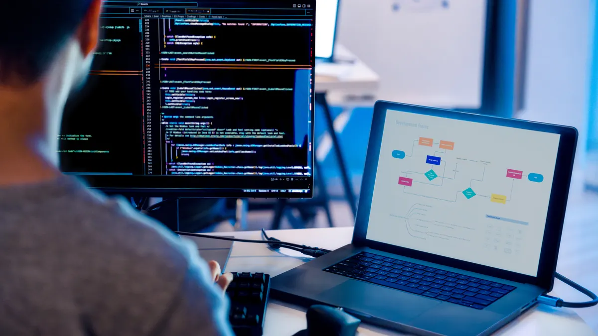 a software developer writes code while using an external monitor in an office setting