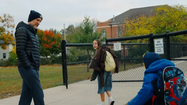 A superintendent greets elementary students outside of their school as they arrive on a fall morning.