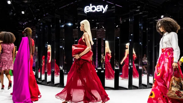 Models wearing bright colors walk the runway in front of mirrors.