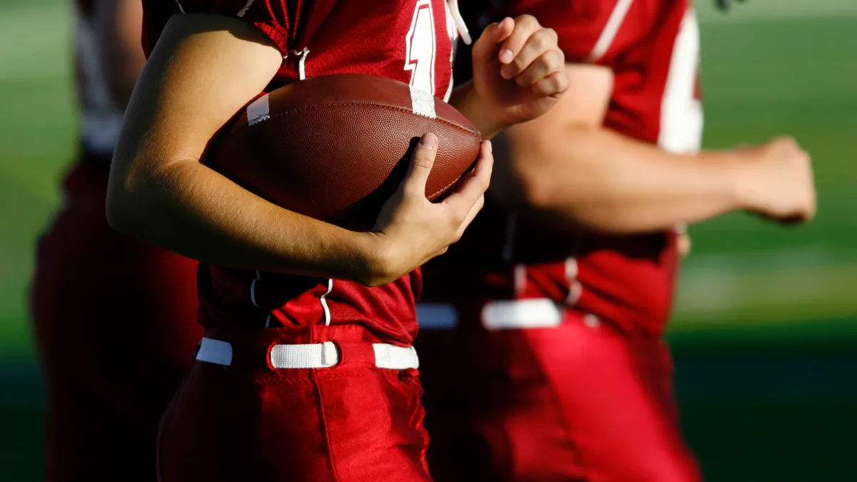 A football player cradles a football.