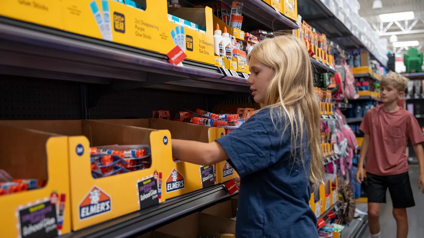 Children shopping for school glue supplies at Walmart.