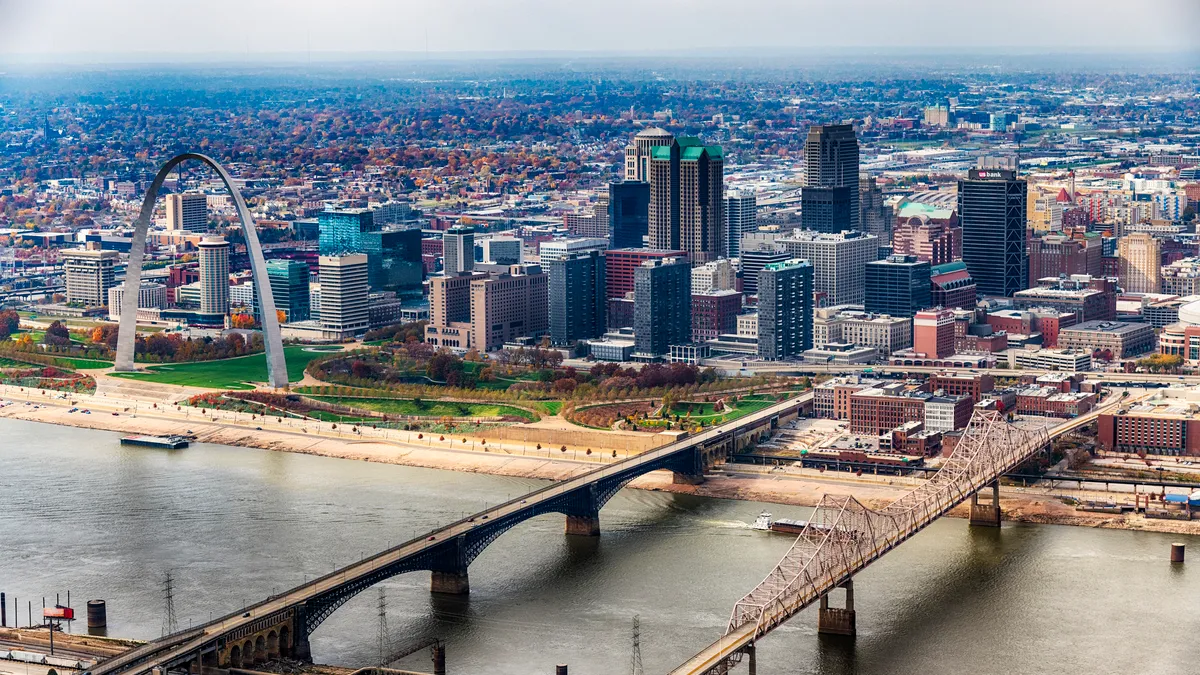 The St. Louis cityscape of buildings, bridges and Gateway Arch are shown from afar.